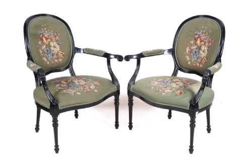 a pair of ebonised armchairs with embroidered tapestry covers