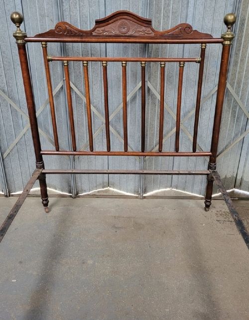 A Victorian double bedstead crafted from turned walnut timber featuring carved panels, decorative brass rings, and brass finials on the headboard and footboard. View II