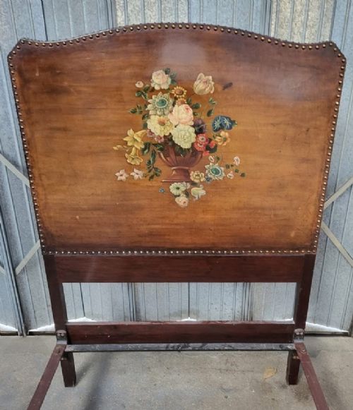 An Edwardian single bedstead with warm brown leather headboard and footboard featuring hand-painted floral urn motifs and brass studding. View II