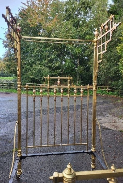 fig 1. An antique Victorian king-size brass half tester bedstead featuring turned posts, decorative porcelain mounts, and an elevated canopy frame structure.