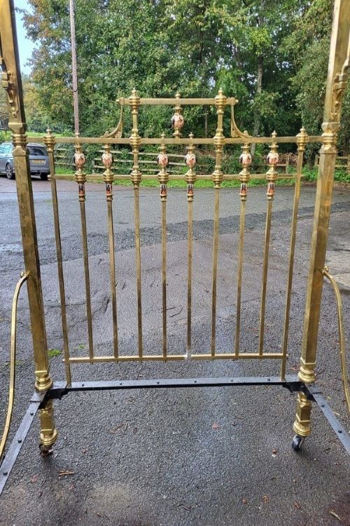 An antique Victorian king-size brass half tester bedstead featuring turned posts, decorative porcelain mounts, and an elevated canopy frame structure. View III