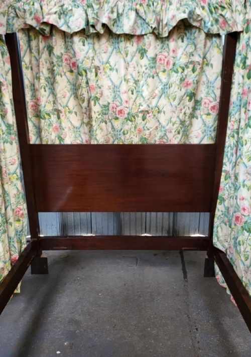 An Edwardian king size mahogany four poster bedstead featuring turned finials, a plain headboard panel, and floral textile curtains. View II