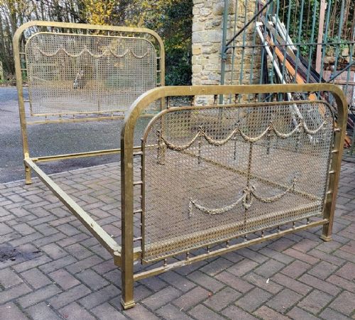 Victorian double size brass bedstead featuring woven mesh panels adorned with cast floral swag and garland motifs on the headboard and footboard. View II