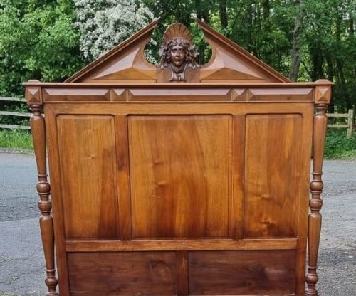 A 19th-century French carved walnut king size bedstead featuring a high panelled headboard topped with a carved face pediment and geometric starburst panels on the footboard. View II