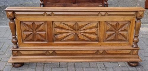 A 19th-century French carved walnut king size bedstead featuring a high panelled headboard topped with a carved face pediment and geometric starburst panels on the footboard. View III