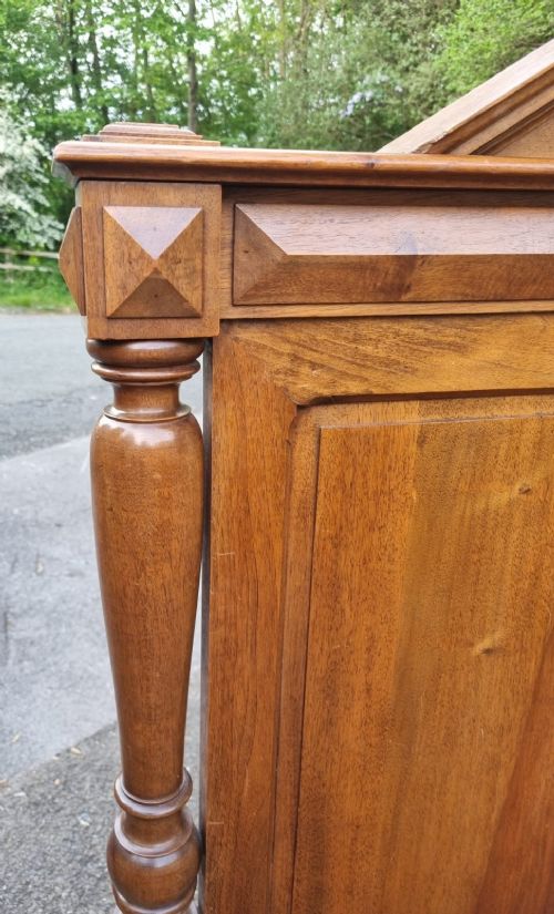 A 19th-century French carved walnut king size bedstead featuring a high panelled headboard topped with a carved face pediment and geometric starburst panels on the footboard. View V