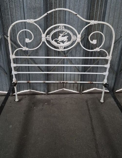 A white painted Victorian double bedstead featuring curved scrollwork and central oval cast plaques displaying a stag motif. View II