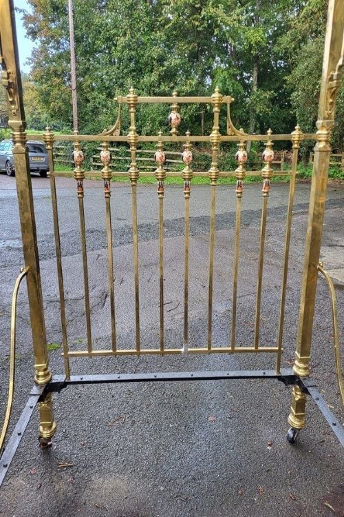 A Victorian king-size half tester bedstead made of brass, featuring ceramic mounts, turned posts, castors, and an overhead canopy frame. View III