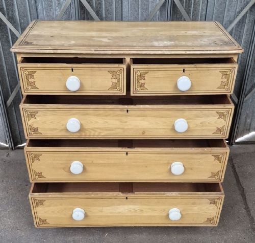 A Victorian pine chest of drawers featuring two short drawers over three long drawers with white ceramic knobs and printed corner line motifs. View II