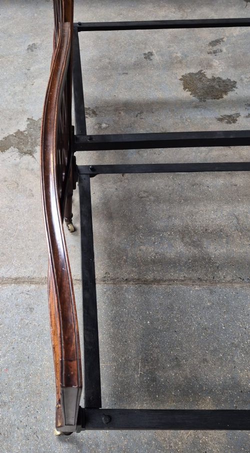A pair of Edwardian mahogany single bed frames featuring pierced lattice upper panels, flame mahogany lower panels, turned legs, and brass castors. View III