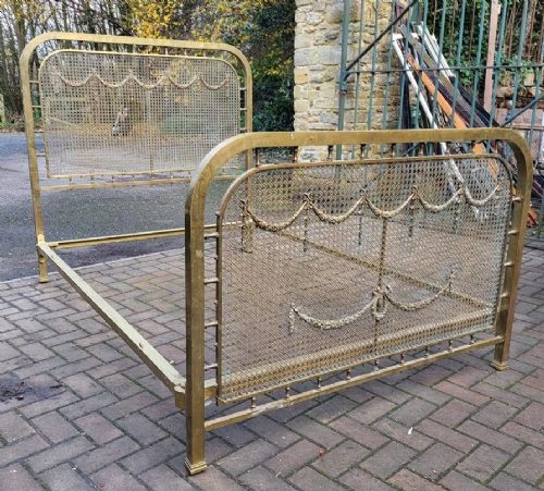 A Victorian double brass bedstead featuring a mesh headboard and footboard adorned with cast festoon swag decoration. View II