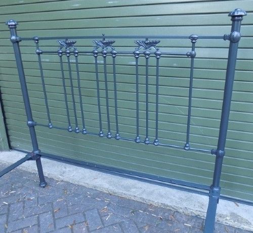 A Victorian dark grey painted iron bedstead with vertical spindles, decorative cast ornamentation, and post finials. View II