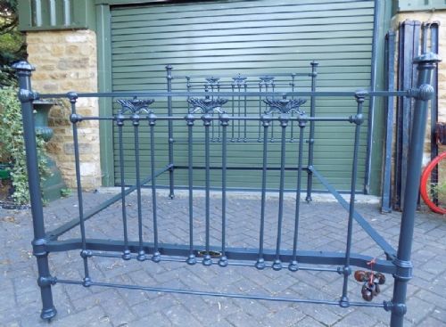 A Victorian dark grey painted iron bedstead with vertical spindles, decorative cast ornamentation, and post finials. View III