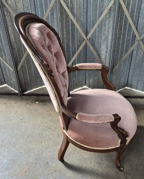 Victorian mahogany armchair upholstered in dusty rose pink button-backed velvet with curved arms and brass casters. View II