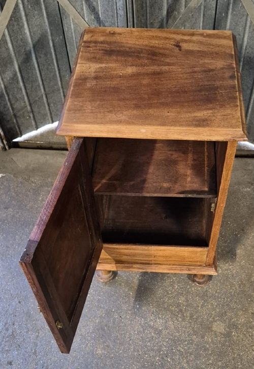 A Victorian walnut bedside cabinet featuring a single panelled door with a brass drop handle, a moulded top, and turned bun feet. View II