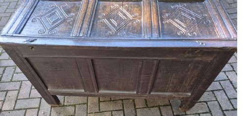 A dark carved oak coffer featuring a three-panel front with carved diamond lozenge patterns and an arcaded top rail. View II