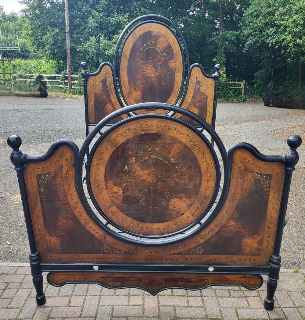 A nineteenth-century Italian tole ware metal bedstead featuring an arched headboard and footboard decorated with painted faux-tortoiseshell motifs and gilded detailing.
