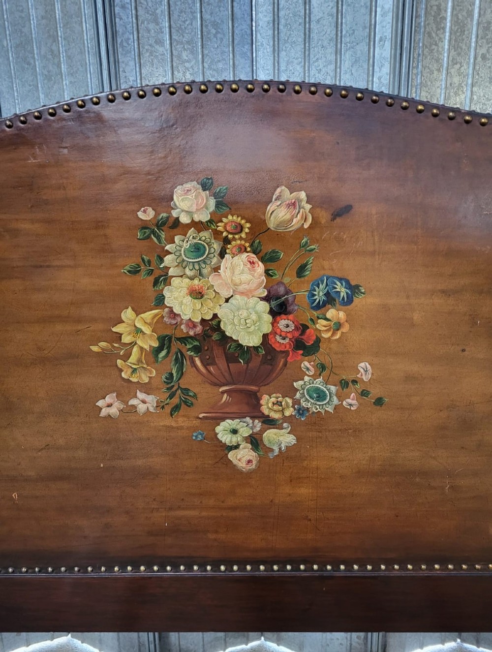 An Edwardian single bedstead with warm brown leather headboard and footboard featuring hand-painted floral urn motifs and brass studding. View III