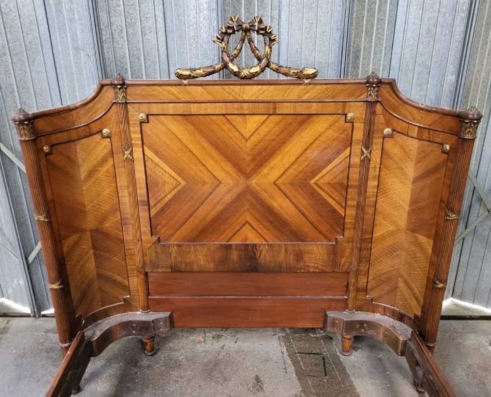 A 19th-century French walnut bedstead featuring geometric quarter-veneered panels, fluted side posts, turned feet, and a carved ribbon top crest. View III