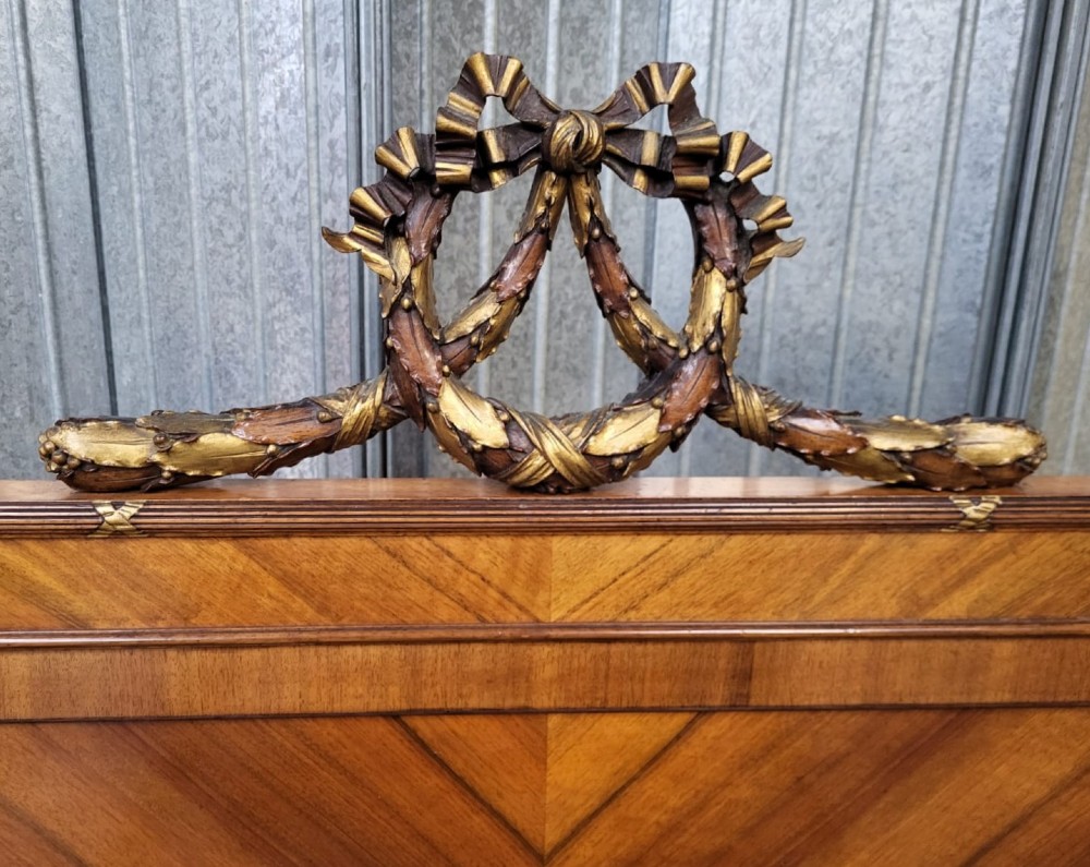 A 19th-century French walnut bedstead featuring geometric quarter-veneered panels, fluted side posts, turned feet, and a carved ribbon top crest. View IV