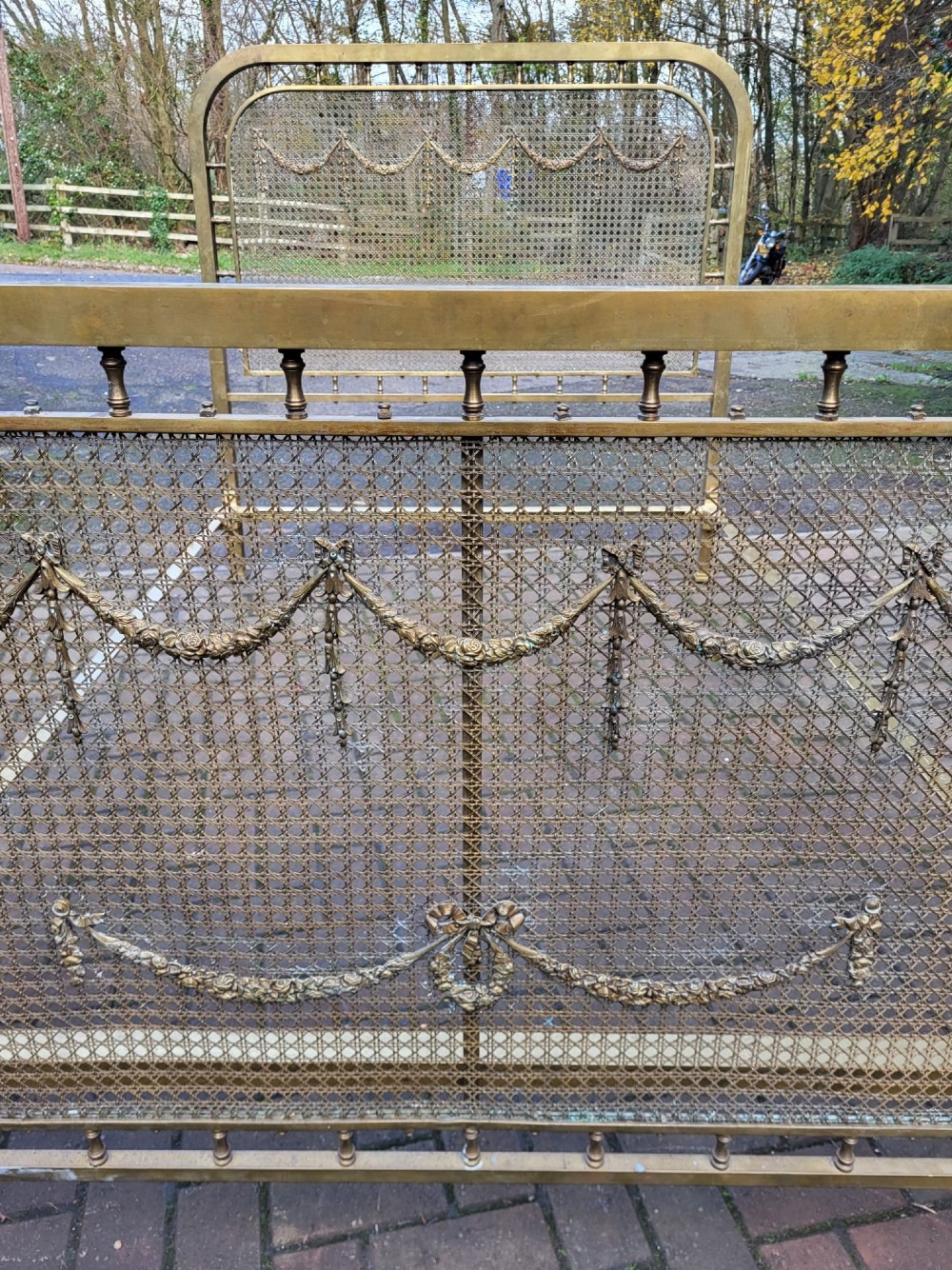 Victorian double size brass bedstead featuring woven mesh panels adorned with cast floral swag and garland motifs on the headboard and footboard. View III