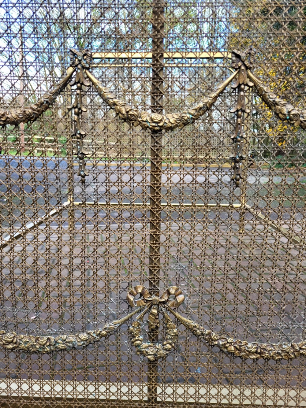 Victorian double size brass bedstead featuring woven mesh panels adorned with cast floral swag and garland motifs on the headboard and footboard. View IV