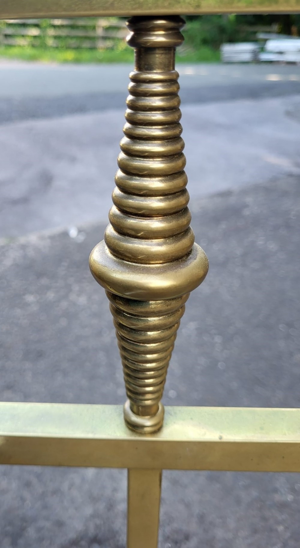 An antique king size brass bedstead featuring geometric rod spindles, circular motifs, urn finials, and castors. View III