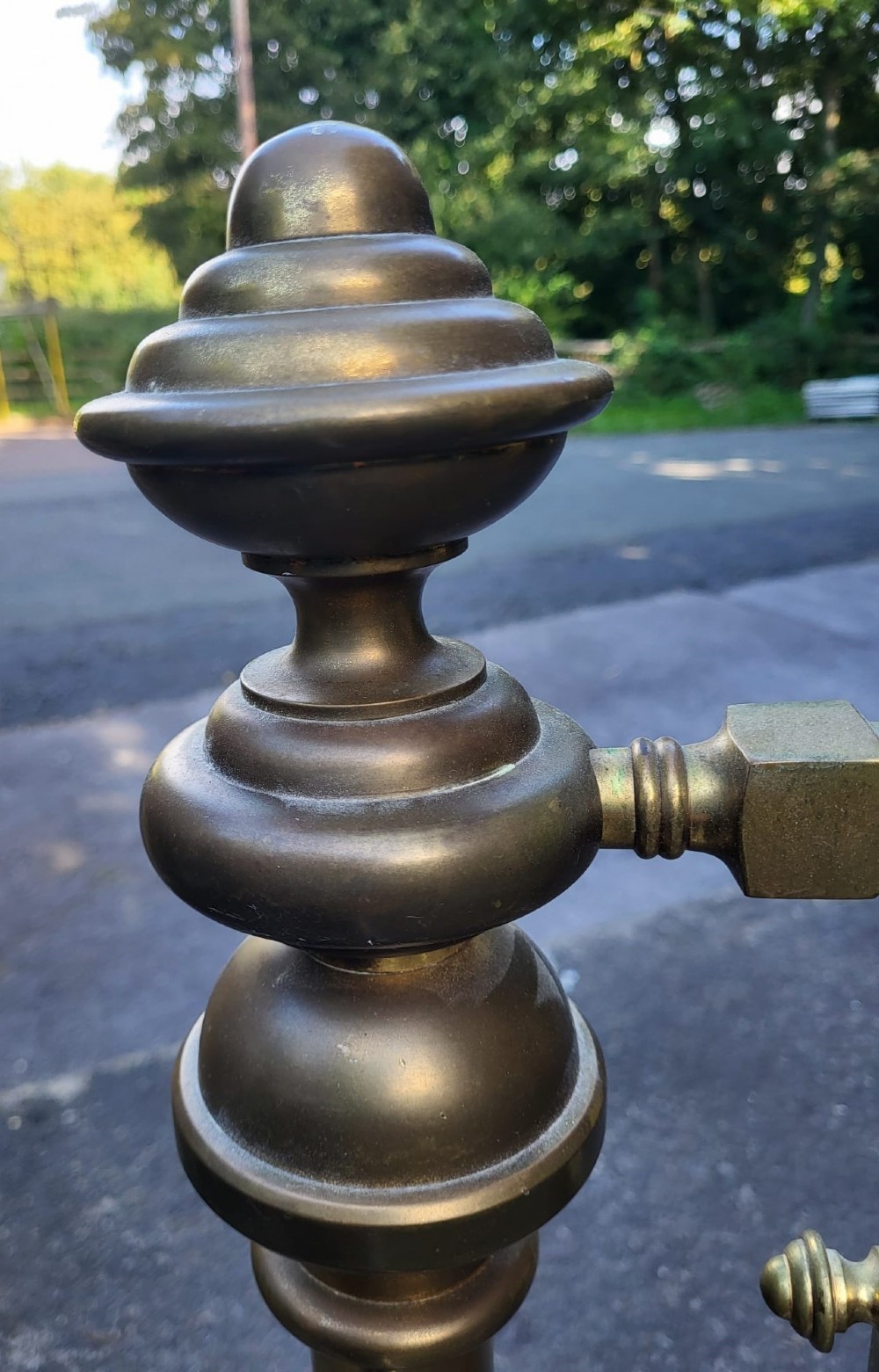 An antique king size brass bedstead featuring geometric rod spindles, circular motifs, urn finials, and castors. View IV
