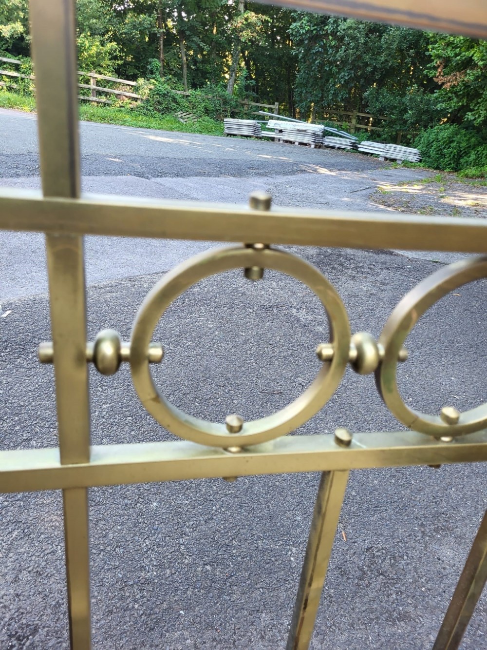 An antique king size brass bedstead featuring geometric rod spindles, circular motifs, urn finials, and castors. View VI