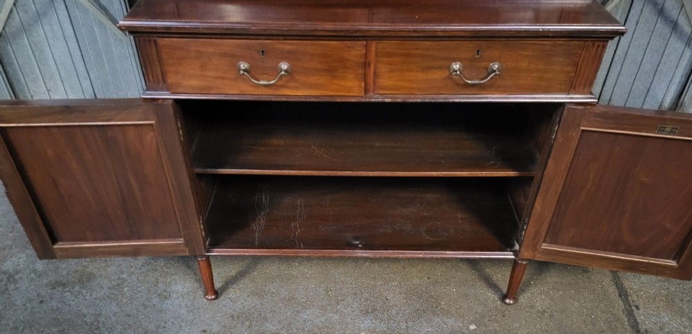 An Edwardian mahogany glazed bookcase featuring geometric astragal glass upper doors above two drawers and a panelled two-door base cabinet. View III