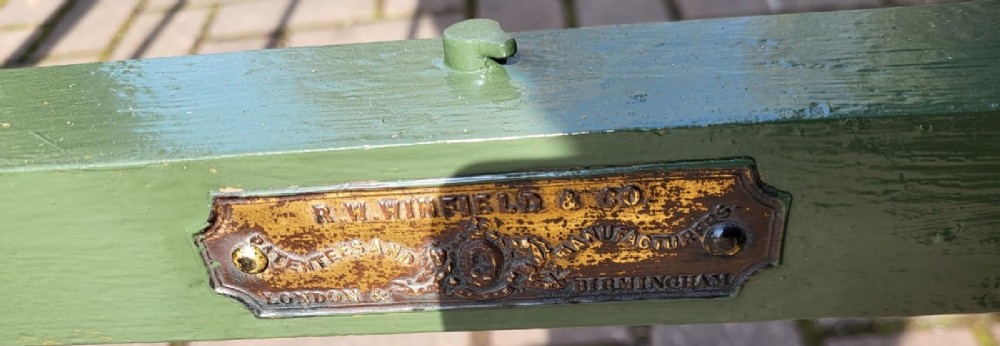 A Victorian small double brass bedstead featuring vertical spindled headboard and footboard panels with turned finials and green painted cast iron rails. View IV