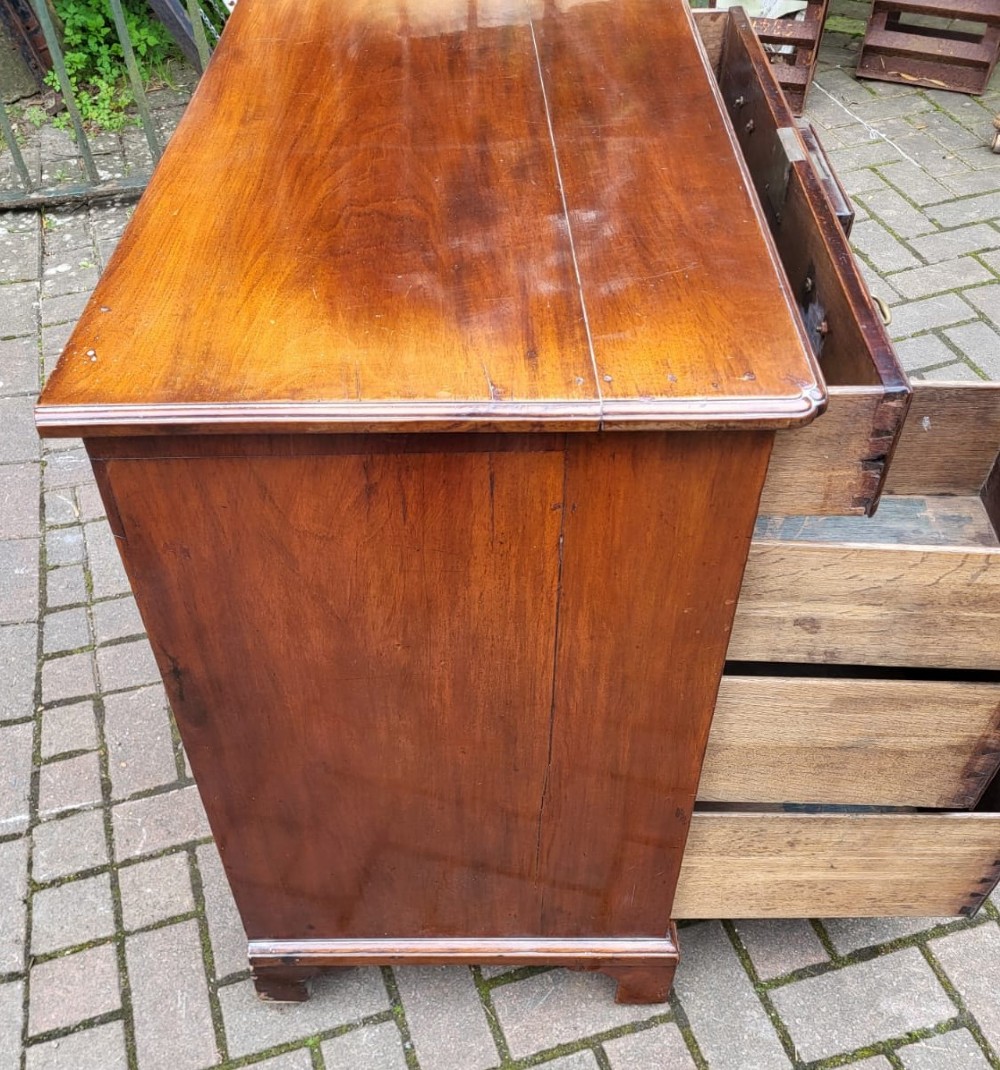 A Georgian mahogany kneehole desk featuring a long top drawer over six side drawers and a recessed central cupboard with brass handles and bracket feet. View III