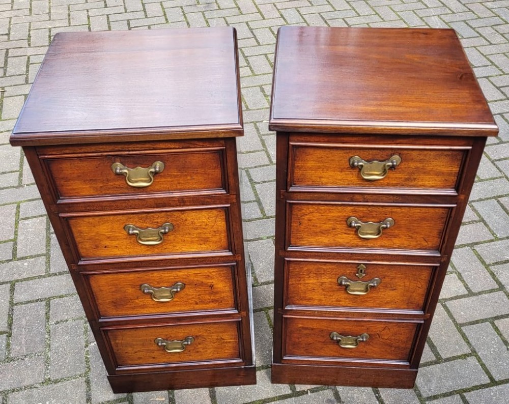 A matching pair of narrow Victorian mahogany bedside cabinets, each featuring four drawers with brass bail handles and a plinth base.