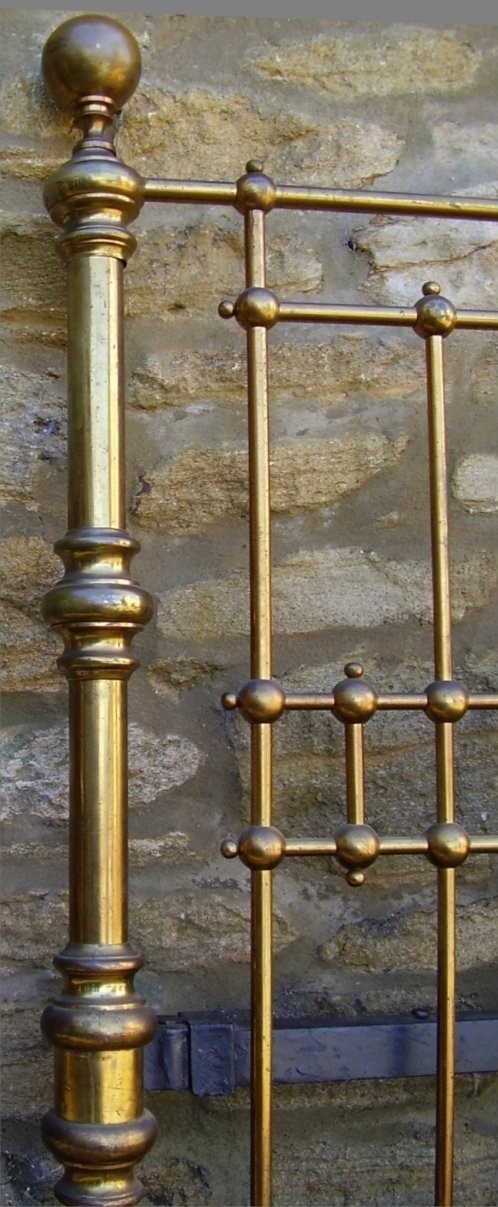 A Victorian king-size brass bedstead featuring decorative vertical spindles, turned ball finials, and a central engraved brass plaque. View II