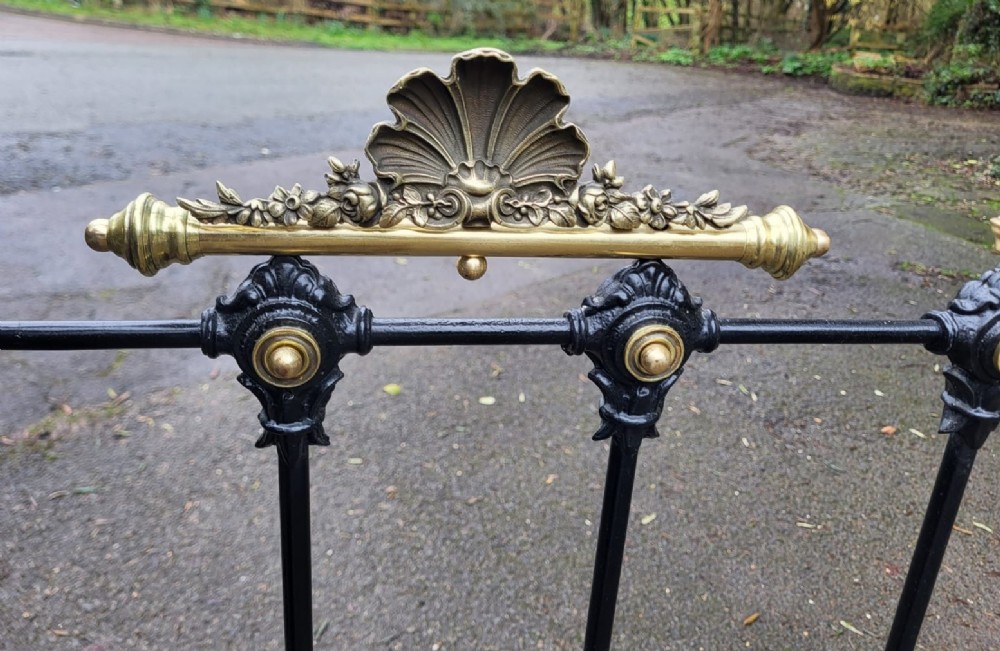 A Victorian double bedstead constructed from black-painted iron vertical spindles with top brass rails, brass finials, and central ornamental brass motifs. View III