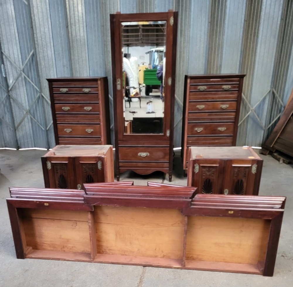 An Edwardian walnut bedroom suite comprising a breakfront compactum wardrobe with a central mirrored door alongside a matching dressing table with drawers and a swivel mirror. View X