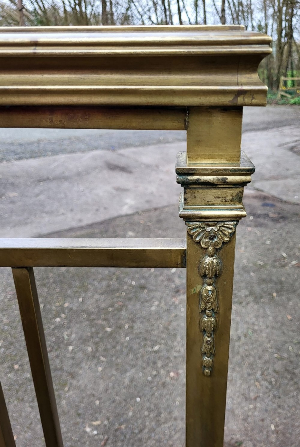 A Victorian king size brass bedstead featuring vertical spindles, an ornamental ribbon swag motif, and brass tubular frames on castors. View III