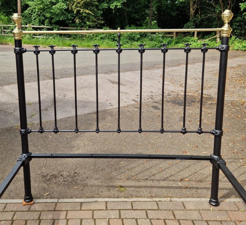A Victorian king size black cast iron and polished brass bedstead featuring decorative central brass medallion detailing and top rails. View II