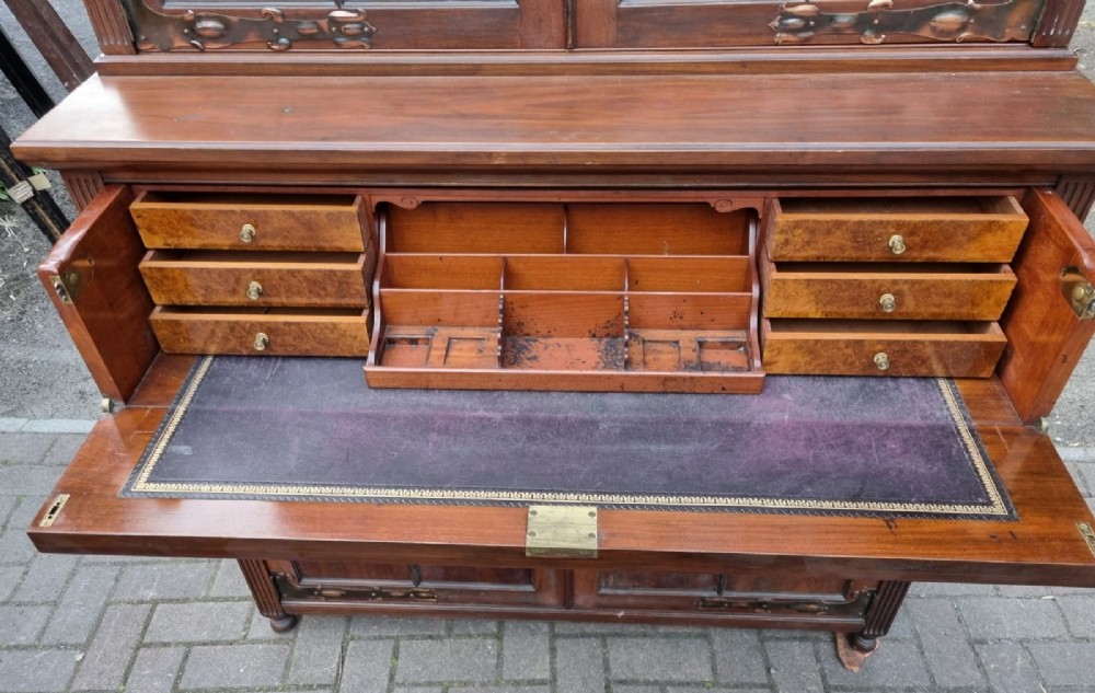 An Edwardian mahogany secretaire bookcase featuring geometric leaded glazed upper doors, metal corner brackets, and carved diamond-panelled lower cupboard doors. View II