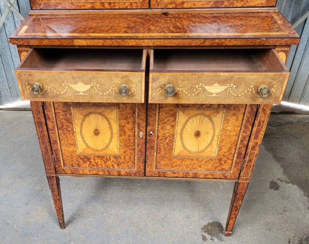 A Victorian birds eye maple bookcase featuring two glazed upper doors, inlaid drawers, marquetry lower cupboards, and tapered square legs. View III