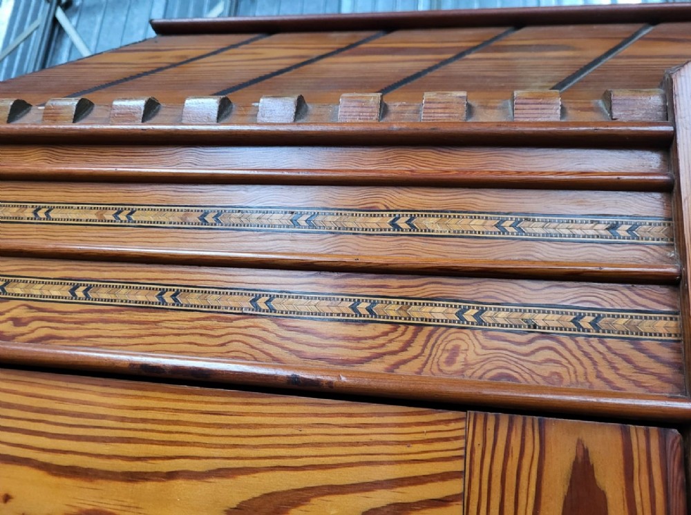 A large Victorian Arts and Crafts pitch pine wardrobe featuring three doors, an arched central mirror, geometric wood inlay, and three drawers at the base. View III