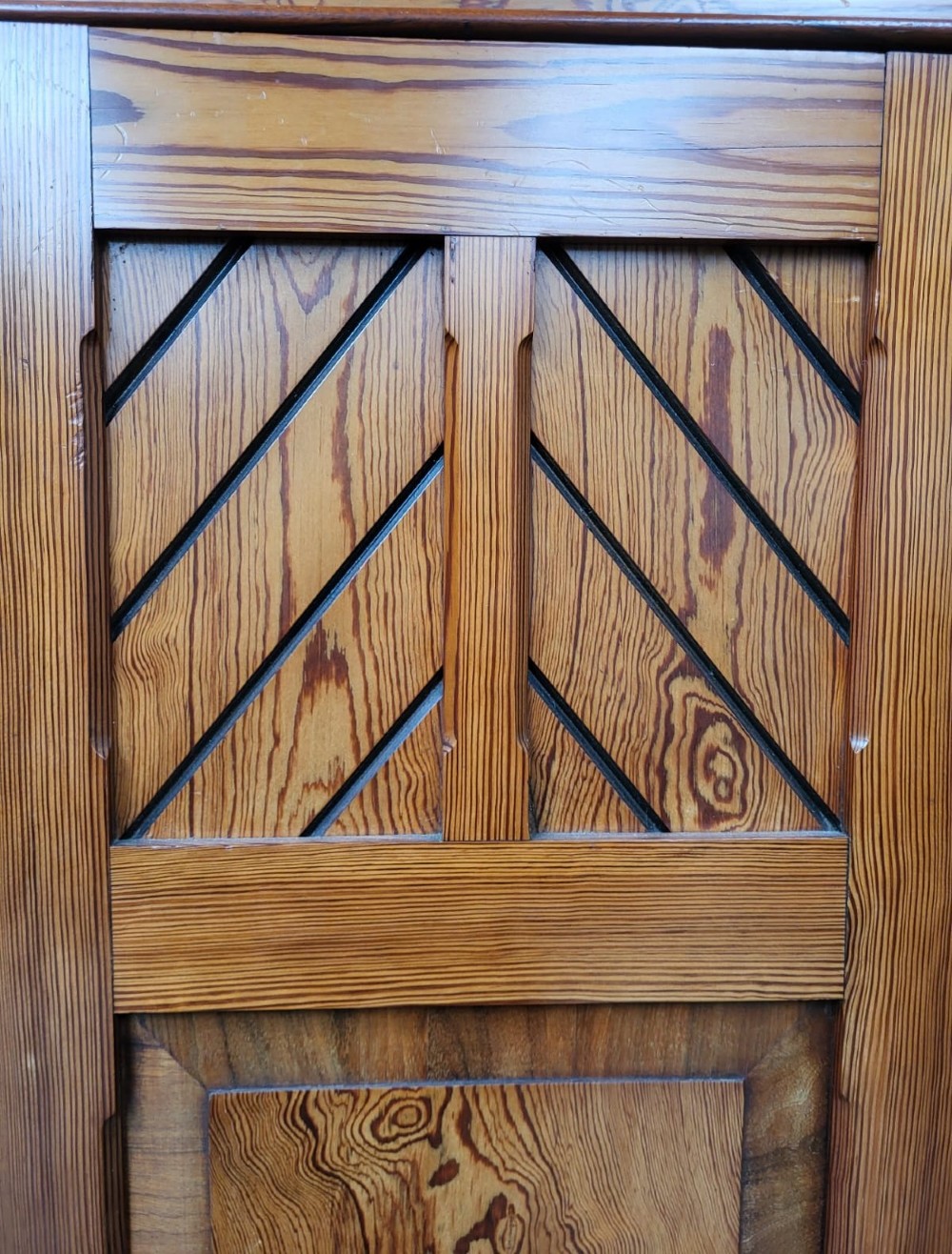 A large Victorian Arts and Crafts pitch pine wardrobe featuring three doors, an arched central mirror, geometric wood inlay, and three drawers at the base. View IV