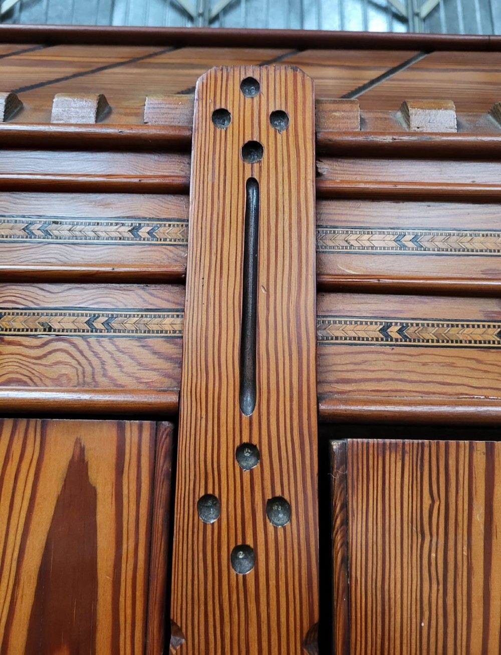 A large Victorian Arts and Crafts pitch pine wardrobe featuring three doors, an arched central mirror, geometric wood inlay, and three drawers at the base. View VI