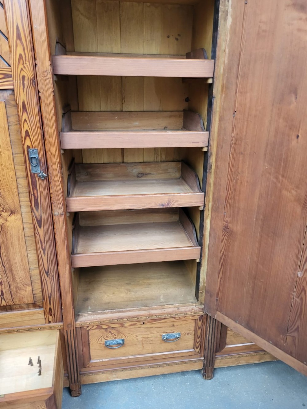 A large Victorian Arts and Crafts pitch pine wardrobe featuring three doors, an arched central mirror, geometric wood inlay, and three drawers at the base. View VIII