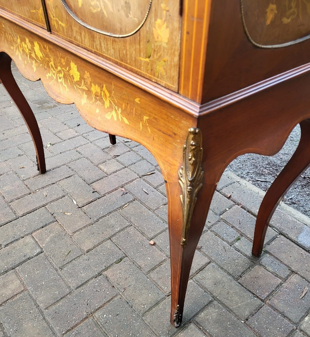 An Edwardian mahogany display cabinet featuring extensive floral marquetry inlay, curved glass doors, a shaped pediment, and cabriole legs. View III