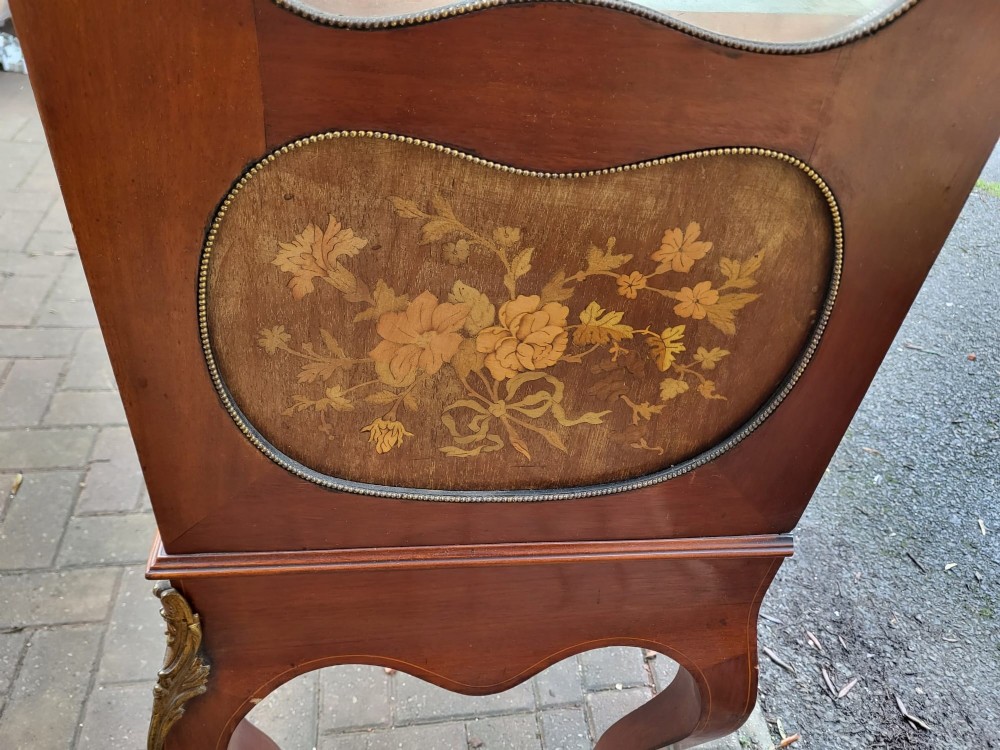 An Edwardian mahogany display cabinet featuring extensive floral marquetry inlay, curved glass doors, a shaped pediment, and cabriole legs. View IV