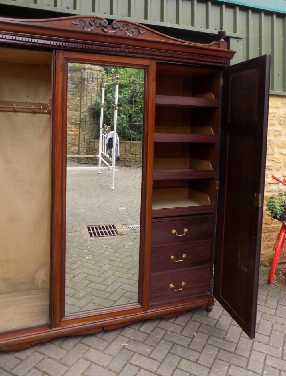 A late Victorian mahogany triple door wardrobe featuring a central full-length mirror, carved diamond relief panels, and a carved crest pediment. View IV
