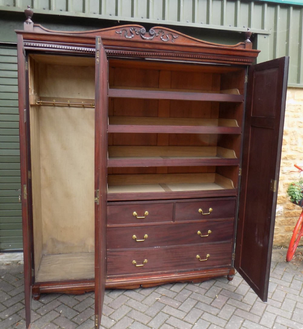 A late Victorian mahogany triple door wardrobe featuring a central full-length mirror, carved diamond relief panels, and a carved crest pediment. View V