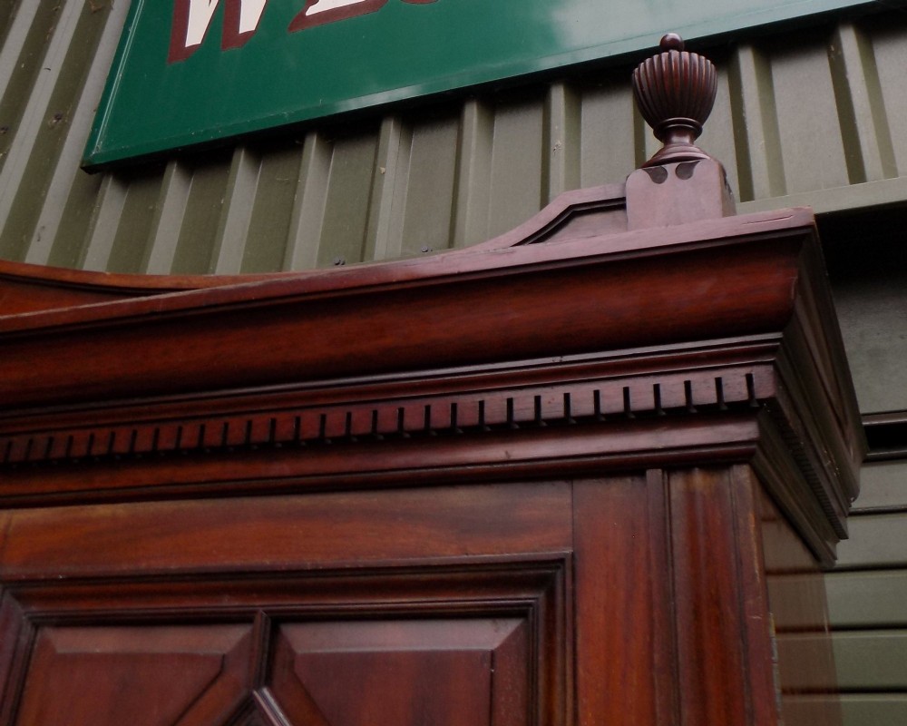 A late Victorian mahogany triple door wardrobe featuring a central full-length mirror, carved diamond relief panels, and a carved crest pediment. View VI
