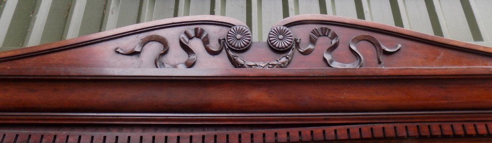 A late Victorian mahogany triple door wardrobe featuring a central full-length mirror, carved diamond relief panels, and a carved crest pediment. View VII